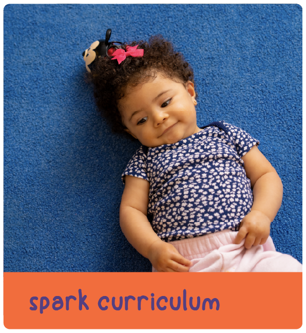 Baby lying on blue carpet with text 'spark curriculum'